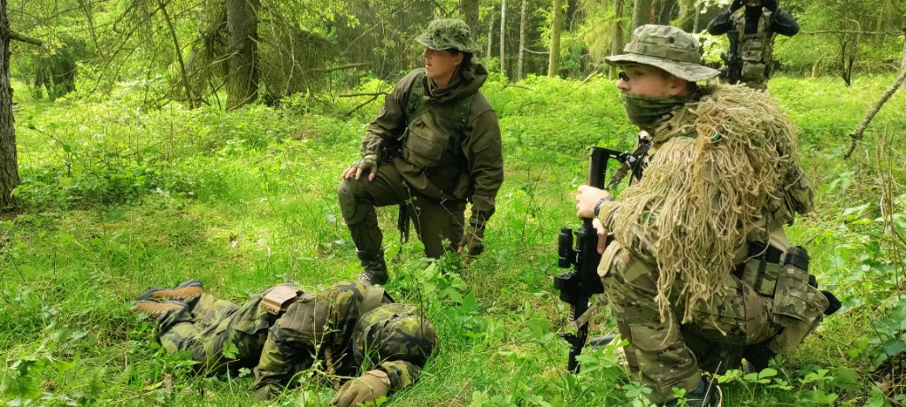 Účastníci v ghillie a taktickom výstroji v hustom lese